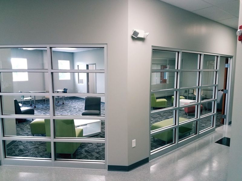 The AAIC library upstairs: two glass-walled rooms with green armchairs, low tables and study desks.